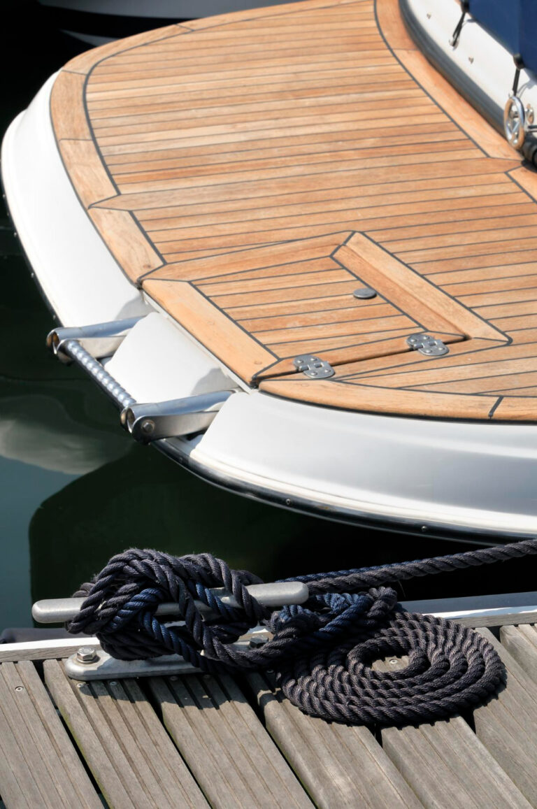 Coperta in teak di una barca a motore ormeggiata, con cima sulla bitta del pontile